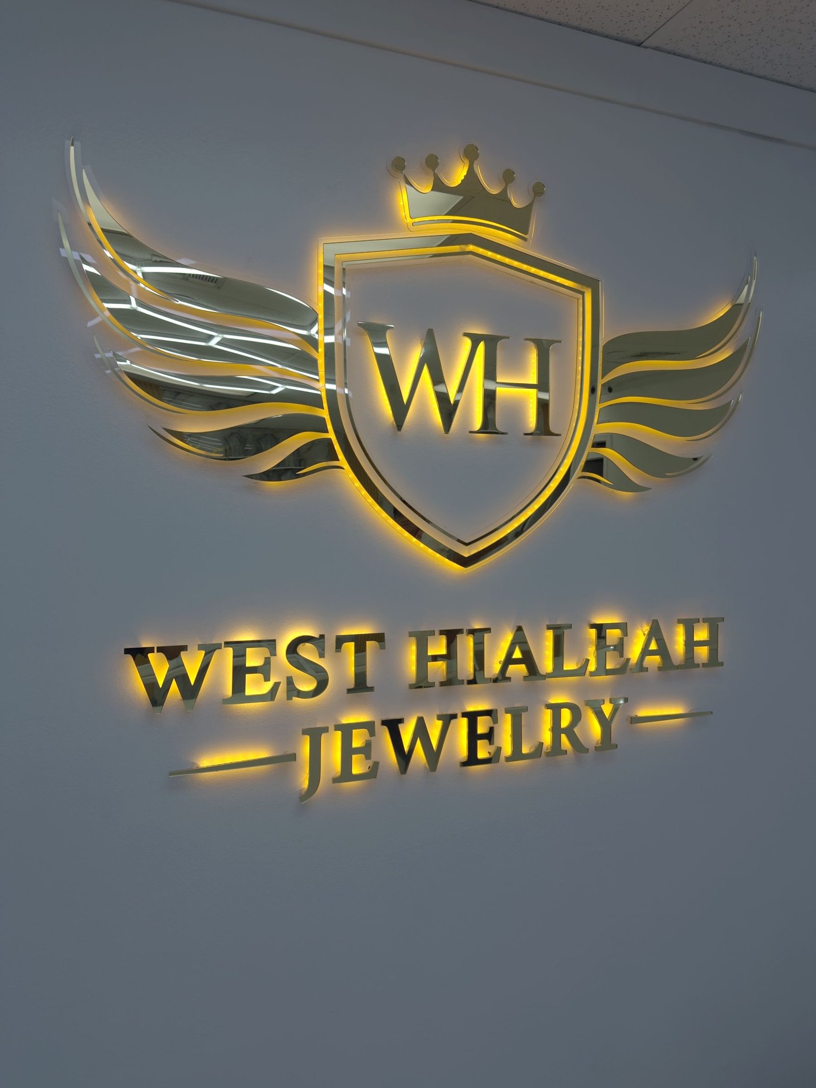 Gold logo sign with crown and wings for West Hialeah Jewelry