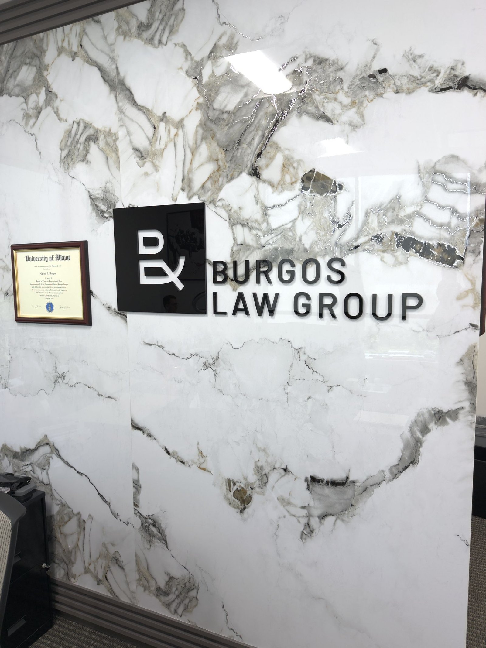 Lobby sign with logo plate for Burgos Law Group on a marble wall